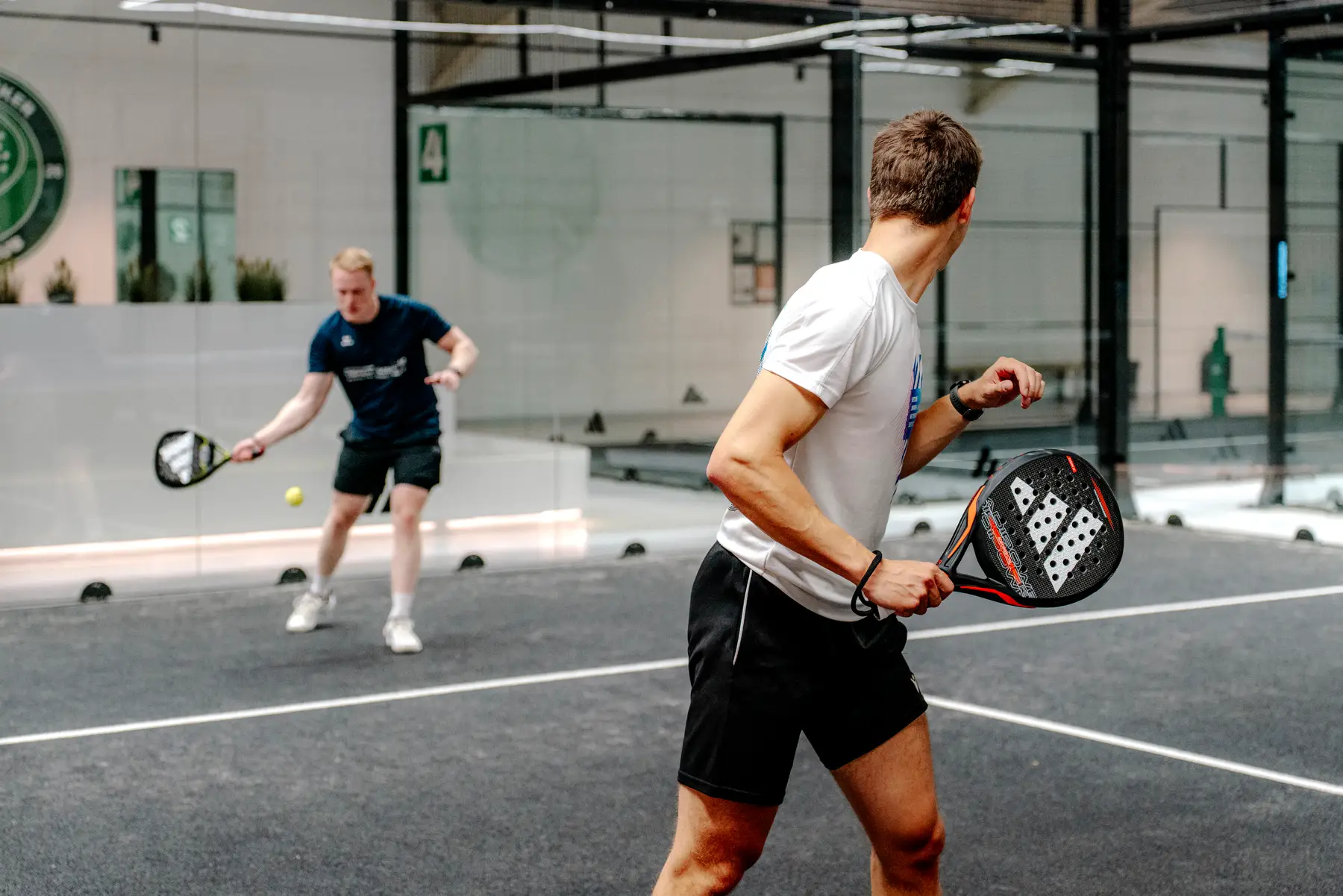 Spieler im Ballwechsel auf dem Padelcourt