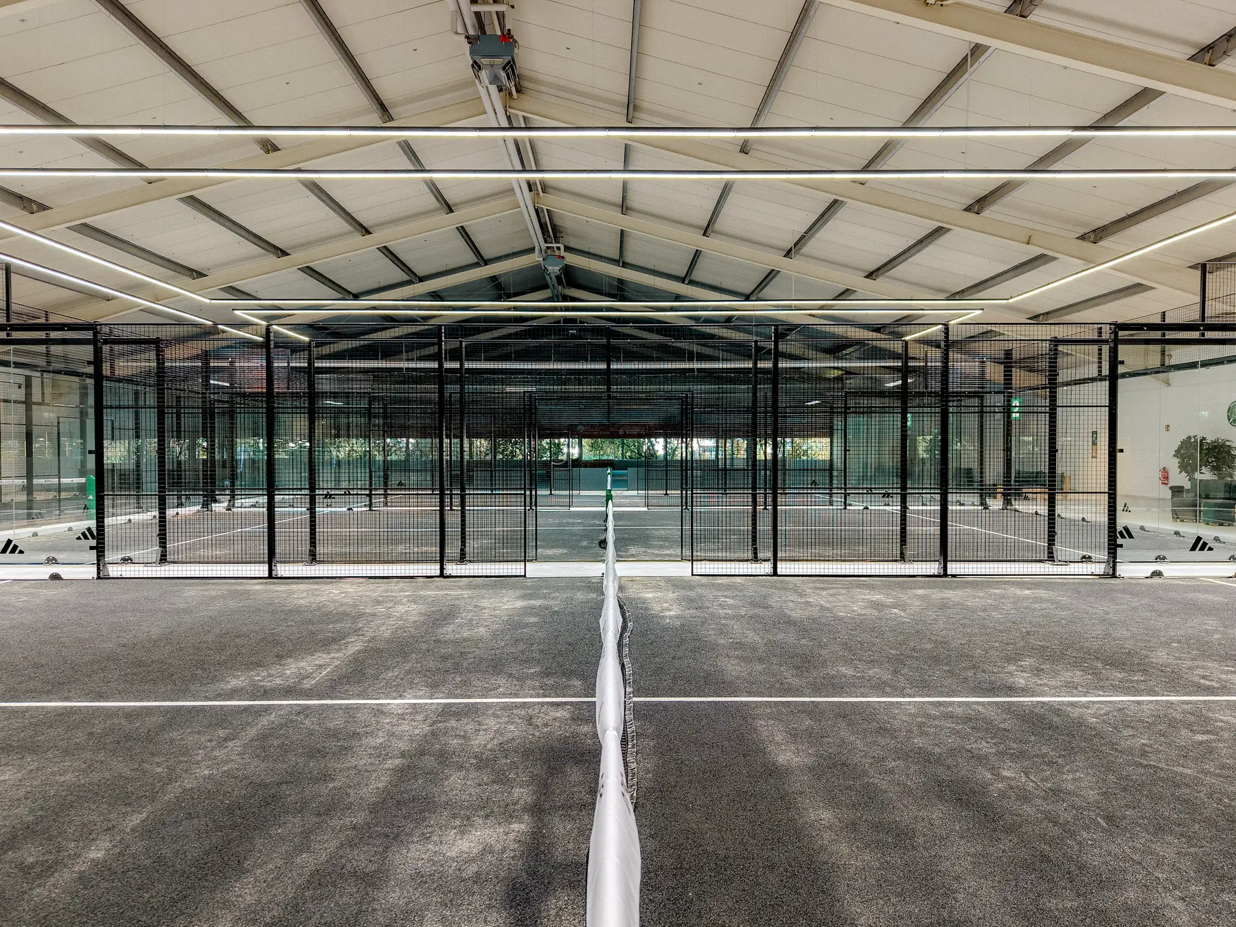 Blick in Netzrichtung über alle Padelcourts in der Halle