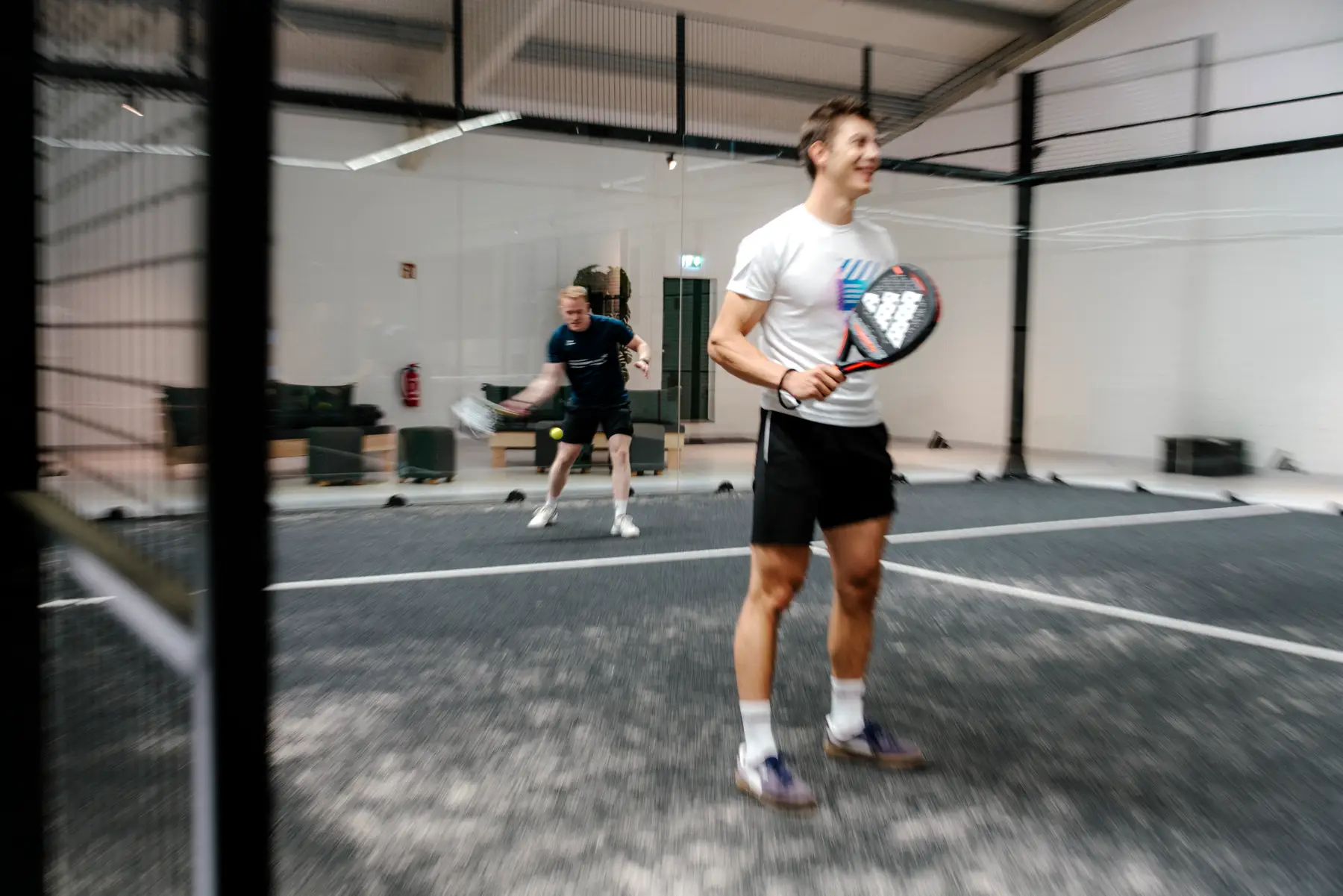 Lachender Spieler auf dem Court, dahinter sein Partner